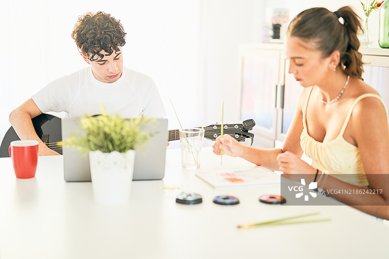 年轻艺术家在家中演奏音乐和绘画图片素材