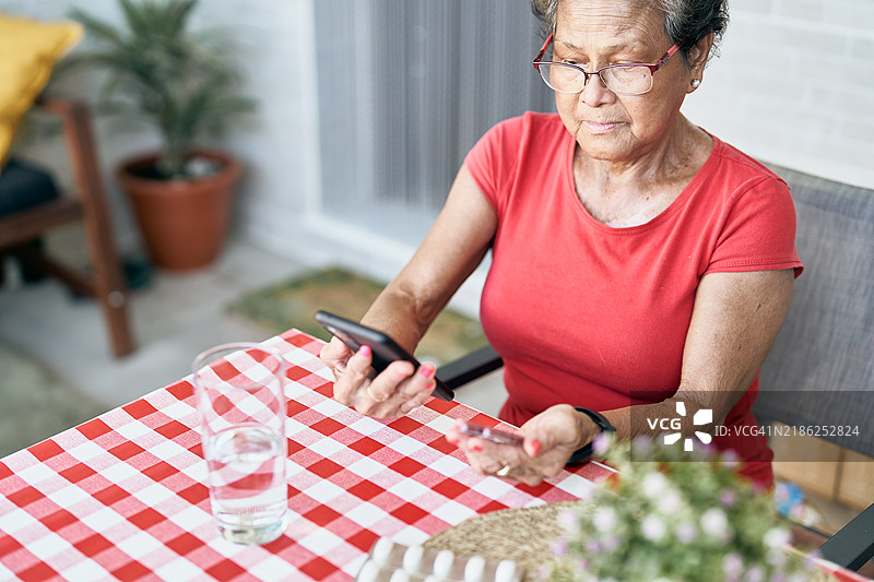 老年女性在家中使用智能手机进行远程医疗咨询图片素材