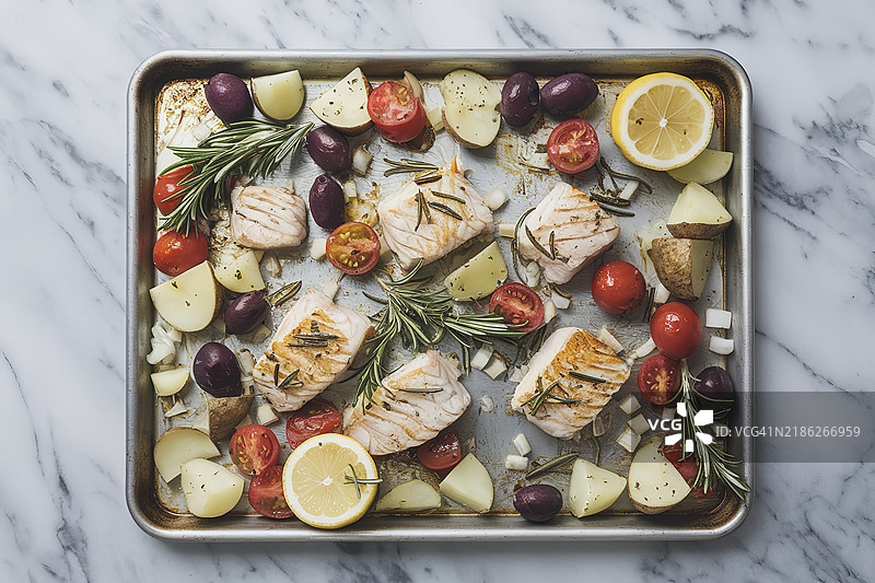 一个孤立的烘焙盘，里面放着鱼块和切丁的土豆图片素材