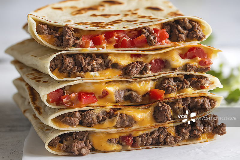 一堆叠放的玉米饼，里面夹着融化的奶酪、碎牛肉和切丁的番茄的照片图片素材
