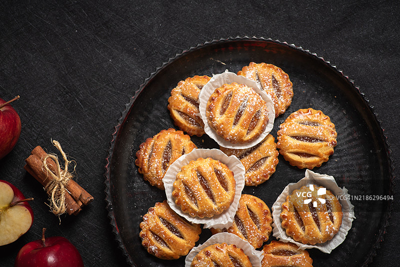自制迷你苹果派，格子顶，放在深色盘子上。图片素材