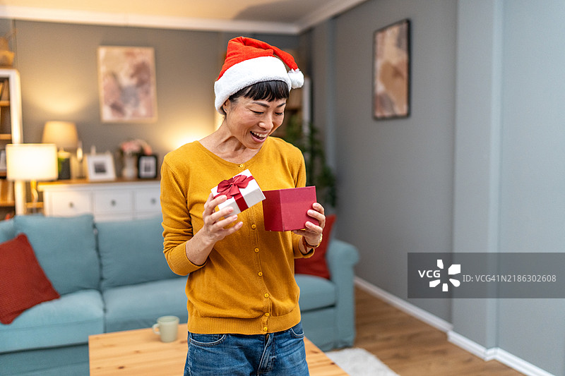 日本女性在圣诞夜开心惊喜地打开礼物盒图片素材