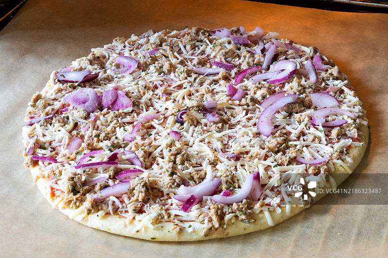 冷冻披萨上放着金枪鱼，放在烤箱的烤盘上图片素材