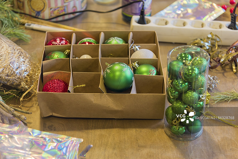 装满圣诞装饰球的纸箱放在木桌上图片素材