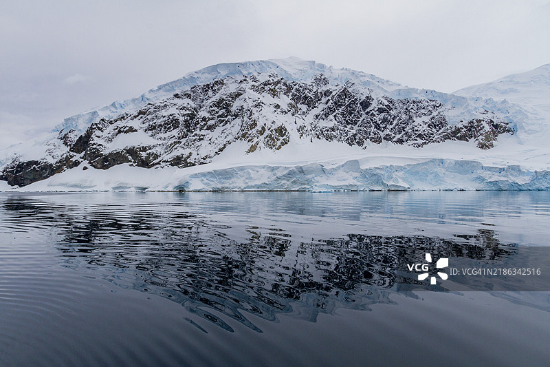 宁可港西侧的南极半岛周围，平静的海面和倒映的山脉景观图片素材