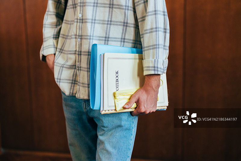 走廊里随意的学生手里拿着笔记本和铅笔图片素材