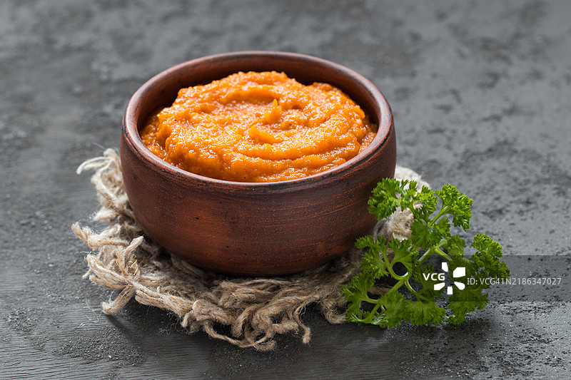 在陶土碗中的南瓜子鱼子酱。放在亚麻餐巾上。配有香 parsley。深灰色背景。乡村风格。俄罗斯美食。图片素材