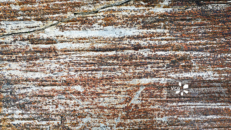 棕灰色石墙特写，有裂痕和风化痕迹。纹理粗糙。阳光。自然色彩。葡萄牙北部皮尼昂。图片素材