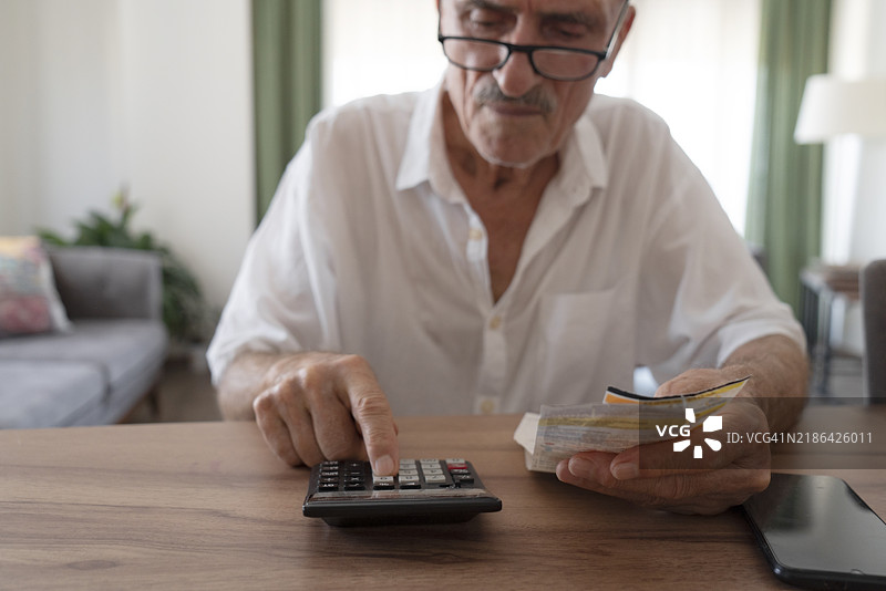 成熟男性在家中查看账单和税务，试图计算并支付它们。图片素材