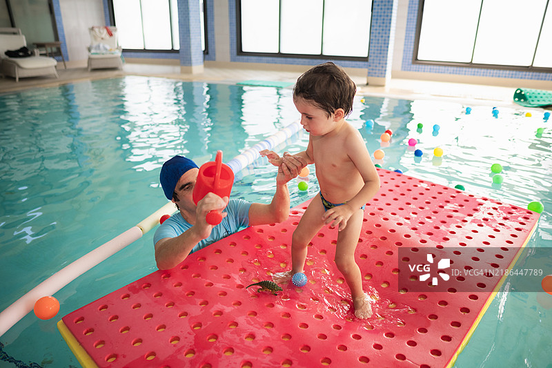 幼儿在泳池的浮垫上保持平衡图片素材