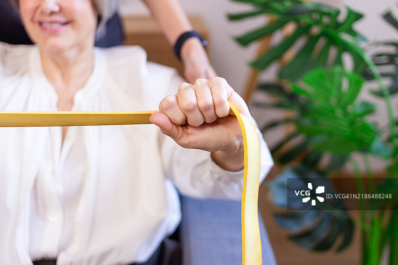 老年女性在家中使用阻力带进行康复锻炼图片素材