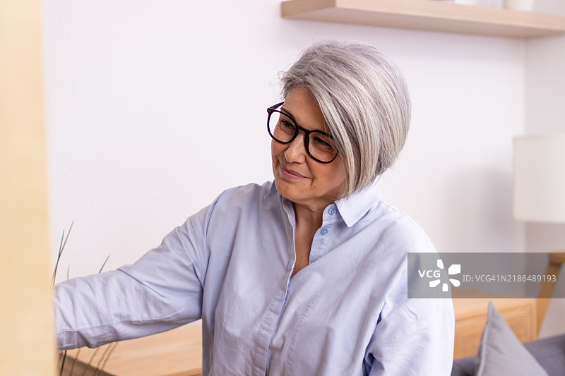 老年女性在现代公寓中调节温控器图片素材