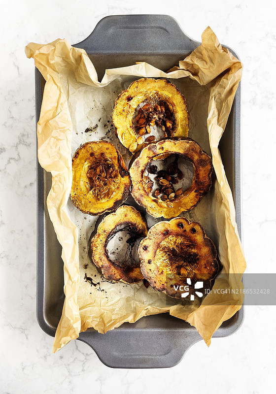 白色背景上的羊皮纸上放着熟透的橡子南瓜切片图片素材