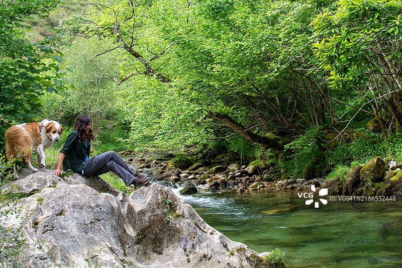 女人和她的狗在河边享受时光。图片素材