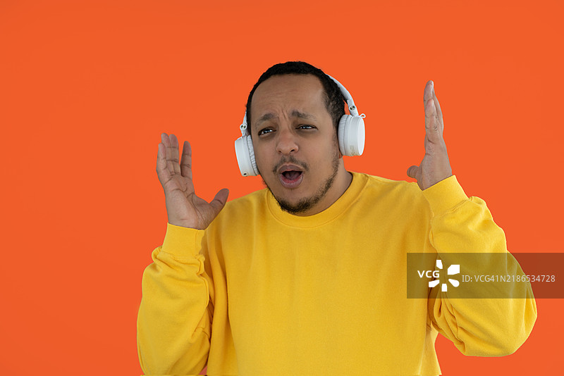 一个戴着耳机的人在单色背景下听音乐，表情惊讶。图片素材