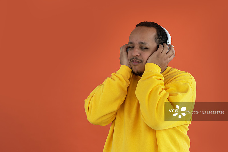一个戴着耳机的人在单色背景下聆听音乐，享受这一体验。图片素材