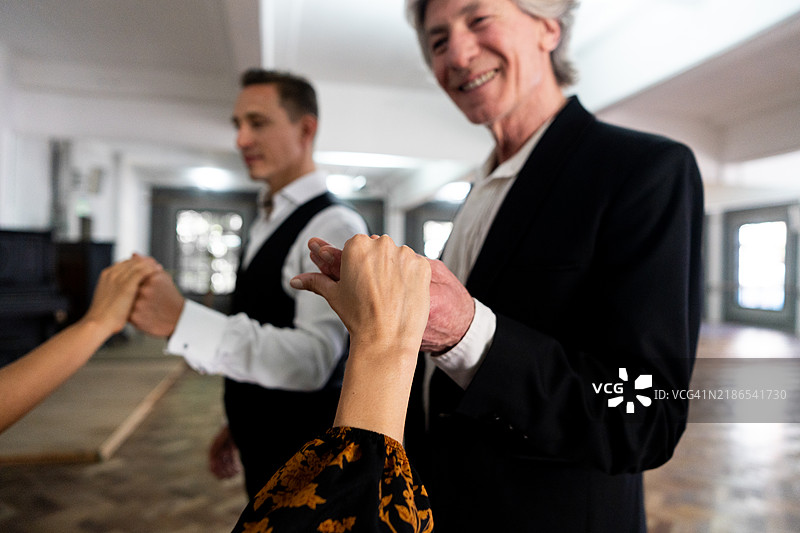 舞蹈工作室中，一位老年男舞者邀请一位女性共舞的特写镜头图片素材