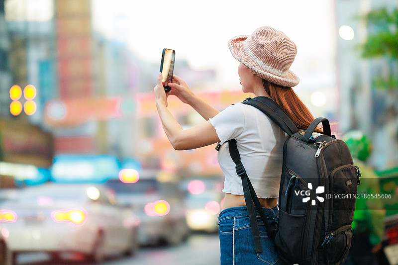 亚洲旅行者背着背包和智能手机,走在繁忙的曼谷街市中,捕捉泰国充满活力的当地购物场景中的文化探索与城市冒险的精髓。图片素材