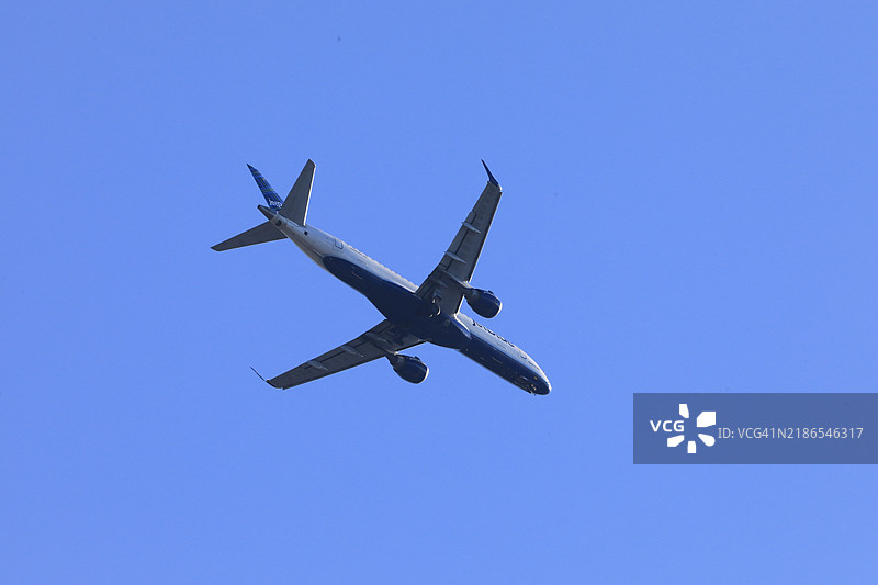 捷蓝航空商业喷气飞机在飞行中，低角度视图图片素材