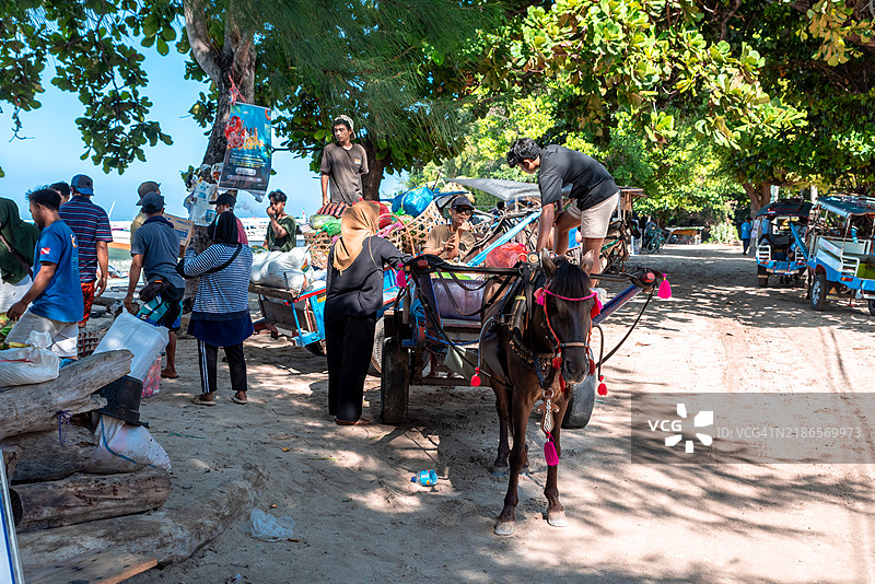 人们在阳光明媚的日子里将货物装载到吉利艾尔的马车上。图片素材