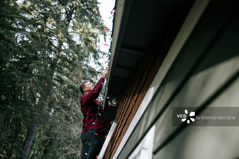 男子在家外墙上挂圣诞灯饰图片素材