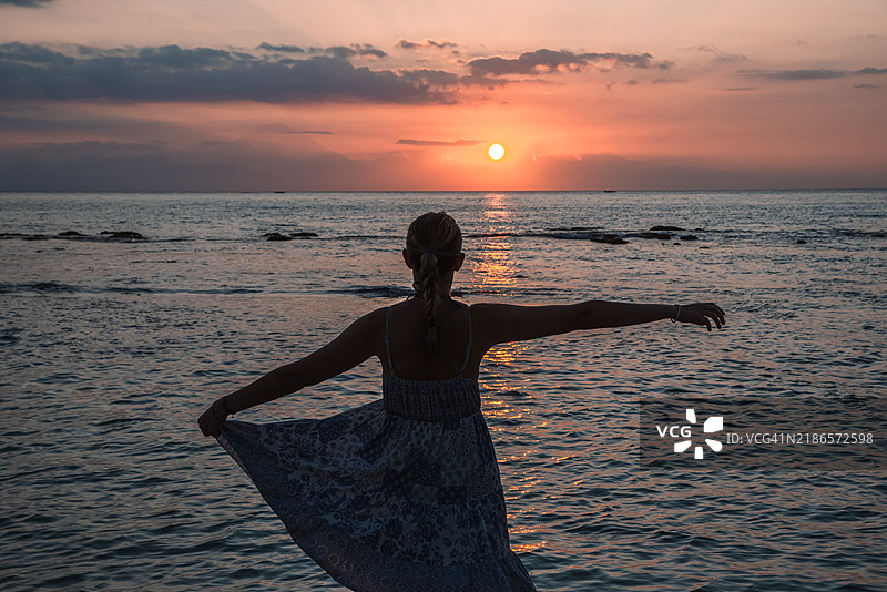 一位女性在Senggigi海滩上跳舞的剪影，欣赏着日落。图片素材