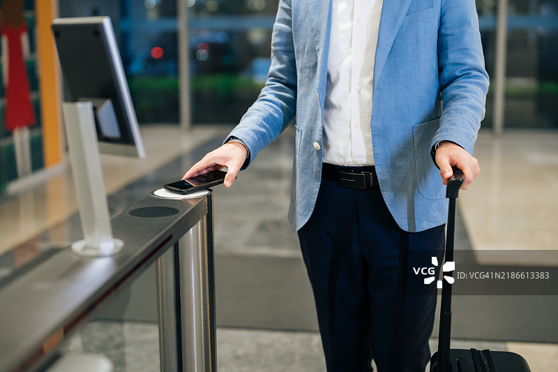 亚洲商人近距离使用智能手机解锁豪华商务大楼入口的门。图片素材