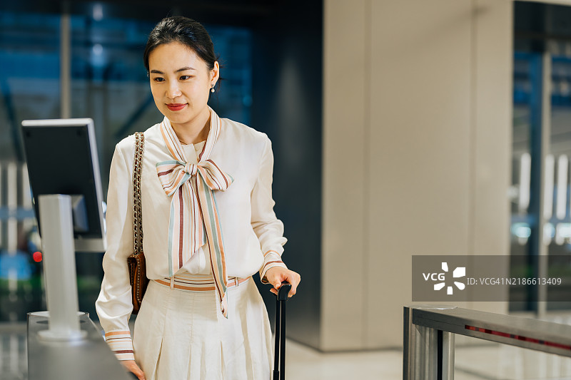 自信的亚洲女商人近距离使用智能手机和面部识别技术解锁豪华商务大楼入口的门。图片素材