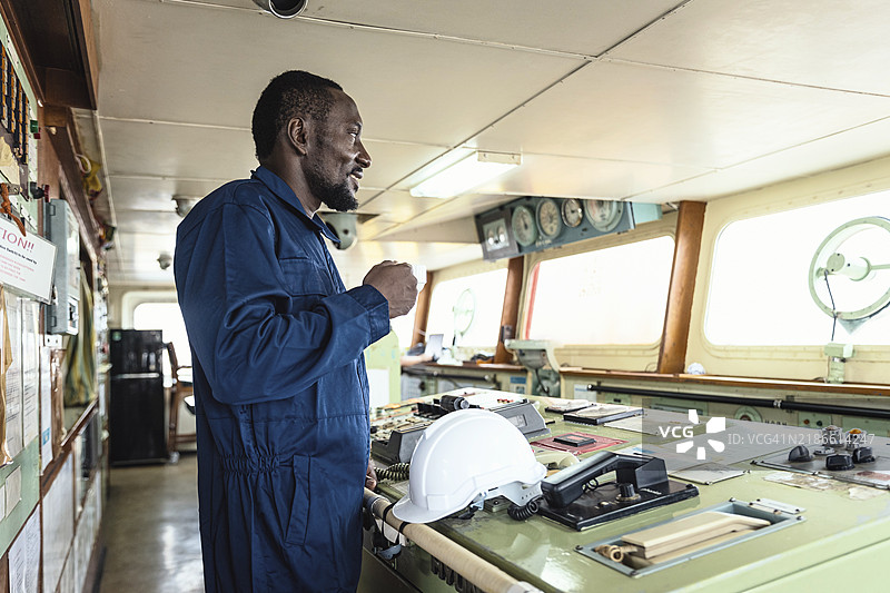 导航员或工程师在集装箱货船的船桥控制室放松，商业物流进出口运输或货物运输。图片素材