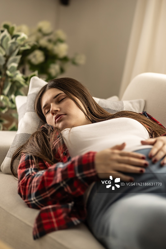 年轻的孕妇在怀孕期间在沙发上休息和睡觉。图片素材