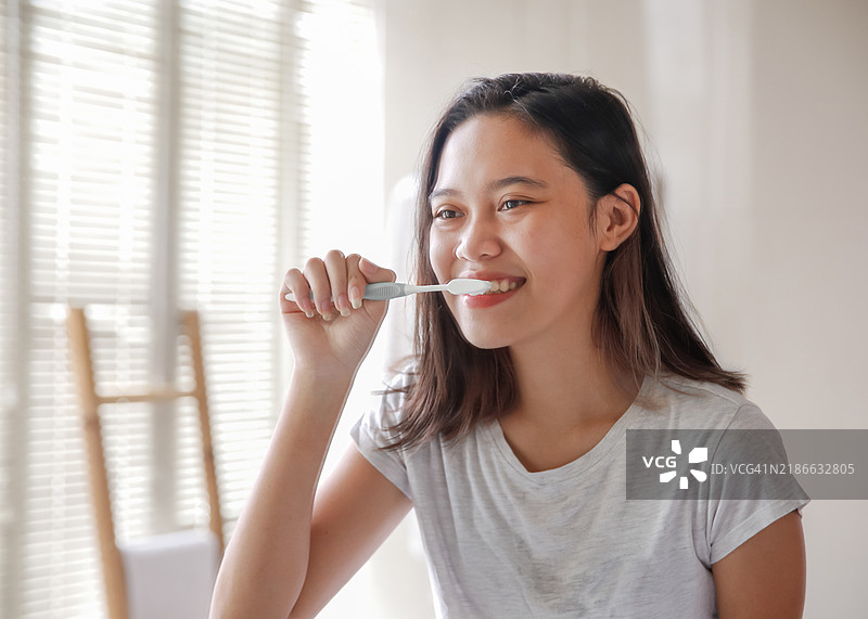 年轻的亚洲女性在浴室镜子前刷牙图片素材