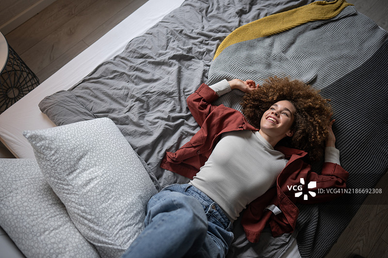 愉快的年轻女性在卧室的床上放松图片素材