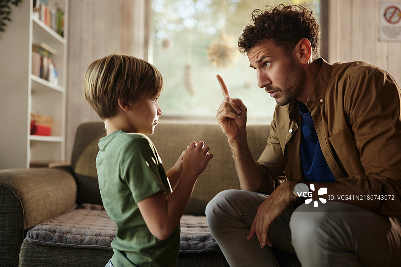 不满的单身父亲在家训斥他的儿子。图片素材