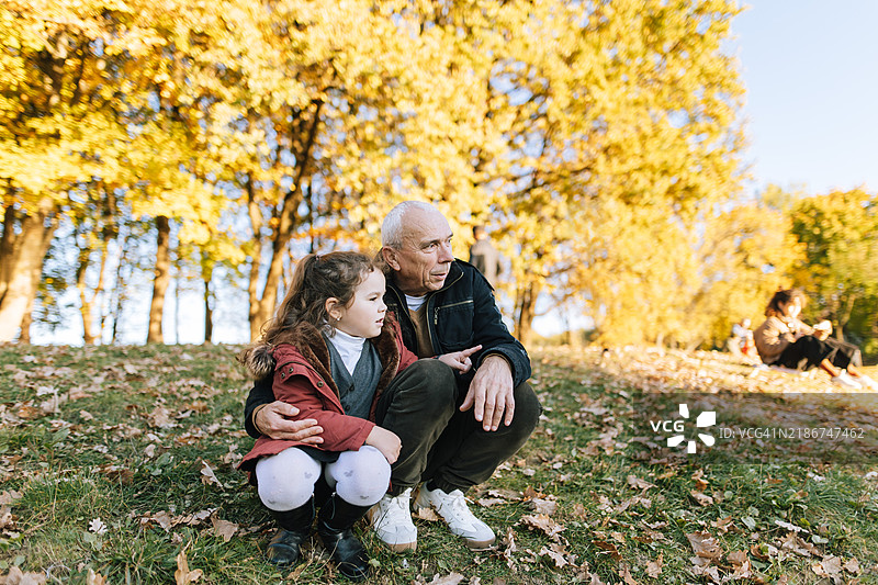 可爱的女孩和她的祖父在秋天一起观看某样东西图片素材