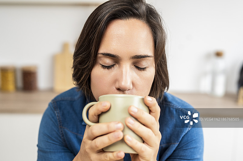 宁静的女性在厨房享受热饮：品味这一刻图片素材