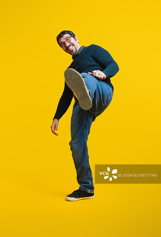 穿着蓝色牛仔裤的男人在黄色背景下的快乐肖像图片素材