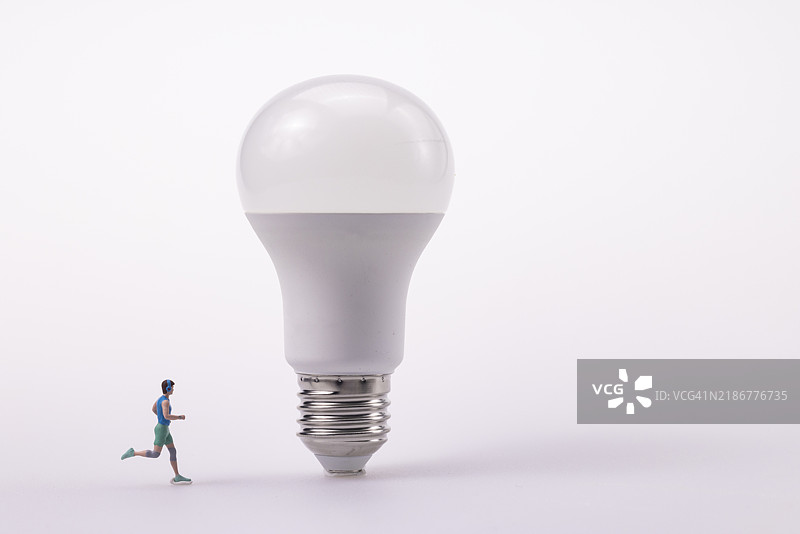 小雕像在灯泡上奔跑图片素材