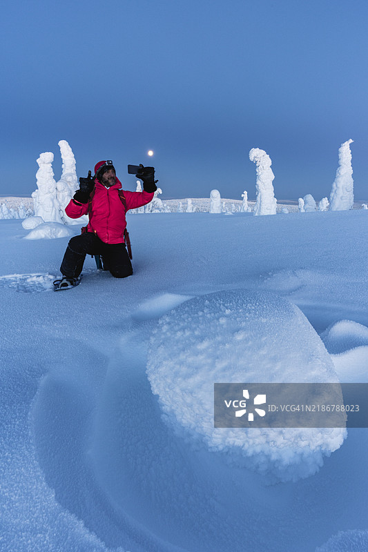 男人在黄昏时分的冬季雪林中自拍图片素材