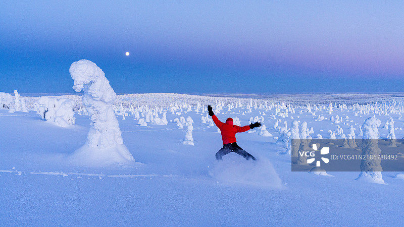 在黄昏时分，顽皮的徒步旅行者在冰雕之间跳跃图片素材