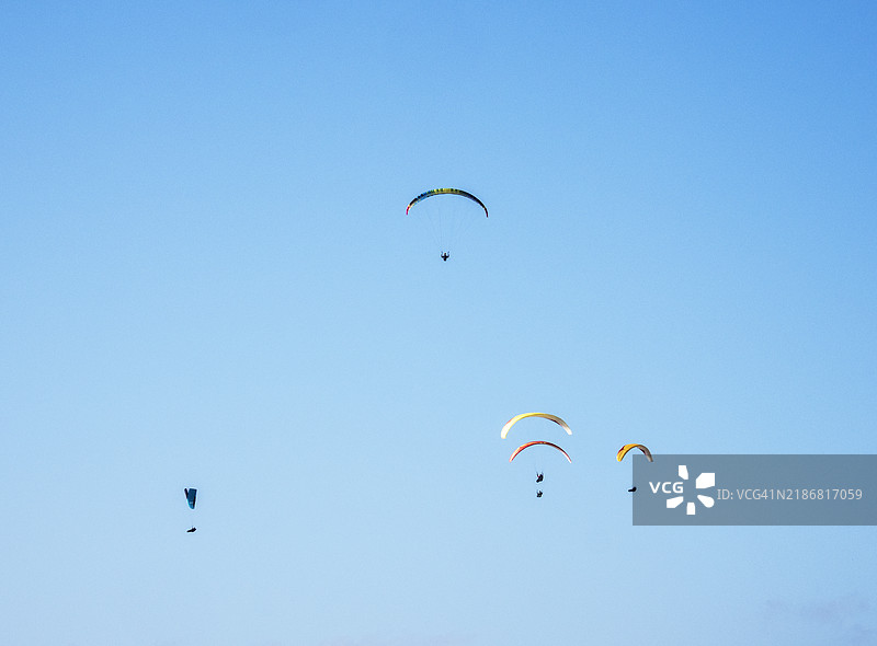 在英国德文郡比尔的比尔头上飞行的滑翔伞运动员。图片素材