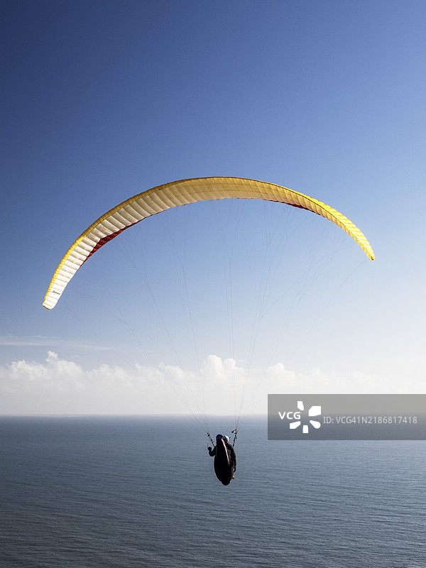 在英国德文郡比尔的比尔头上飞行的滑翔伞运动员。图片素材