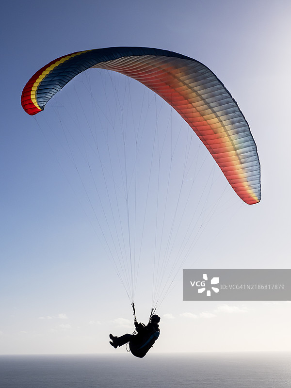 在英国德文郡比尔的比尔头上飞行的滑翔伞运动员。图片素材