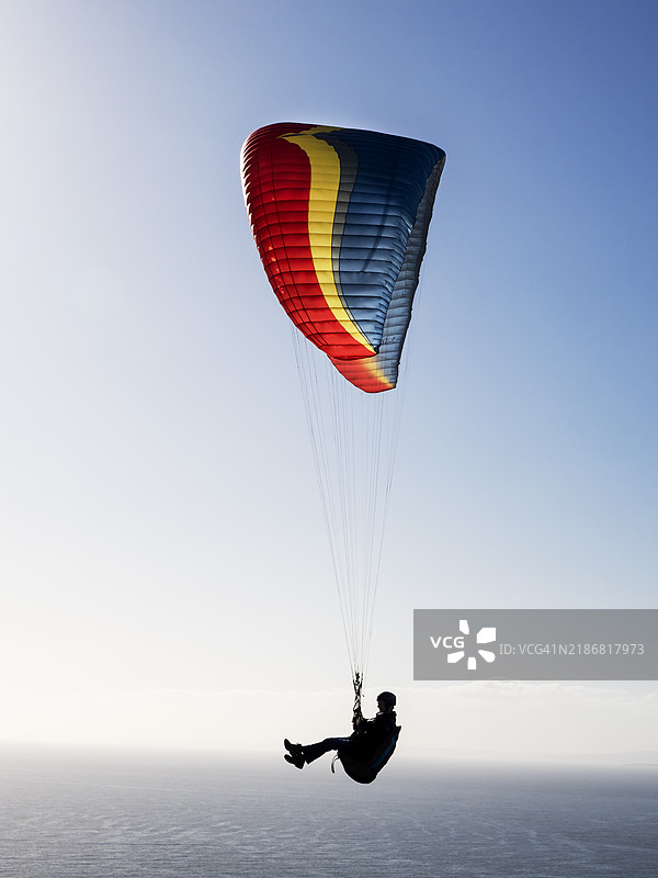 在英国德文郡比尔的比尔头上飞行的滑翔伞运动员。图片素材