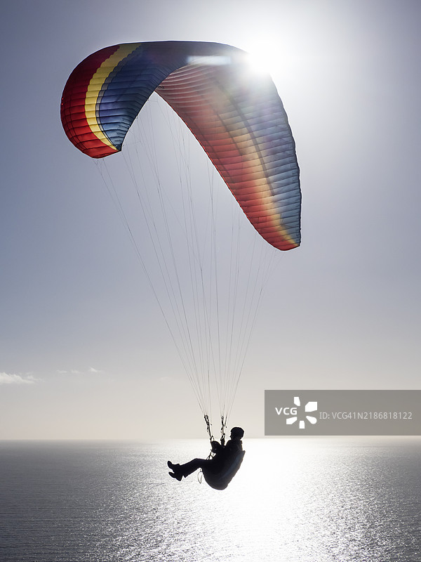 在英国德文郡比尔的比尔头上飞行的滑翔伞运动员。图片素材