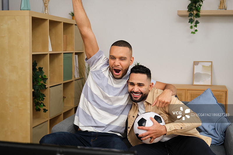 两个朋友在看电视足球比赛时欢呼庆祝图片素材