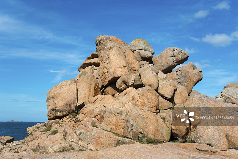 在晴朗的蓝天下，巨大的岩石形成高耸入云，位于法国布列塔尼的佩罗斯-吉雷克的普洛曼纳赫。图片素材