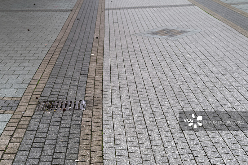 荒废的铺装人行道，带有沟渠覆盖物图片素材