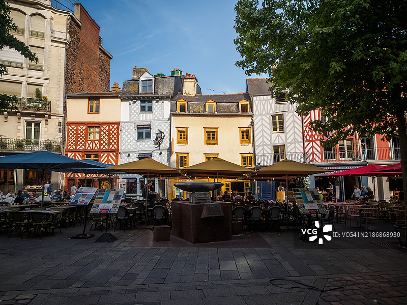 宽角度视野下，雷恩历史区的小石板广场上，五彩斑斓的半木结构建筑内有餐厅和咖啡馆，背景中有一个喷泉，位于法国布列塔尼的伊勒-维莱讷省。图片素材