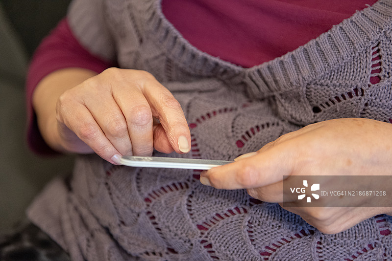 一位老年女性正在做美甲的手。图片素材