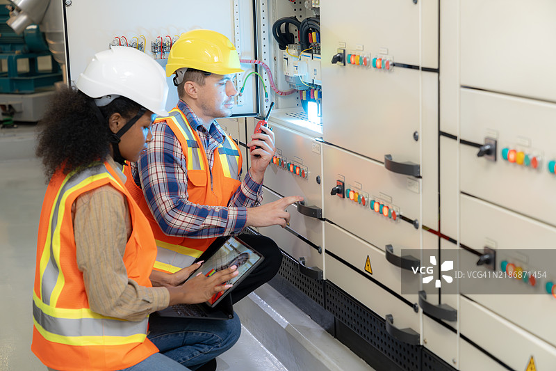 两名电气工程师正在研究一个开关柜图片素材